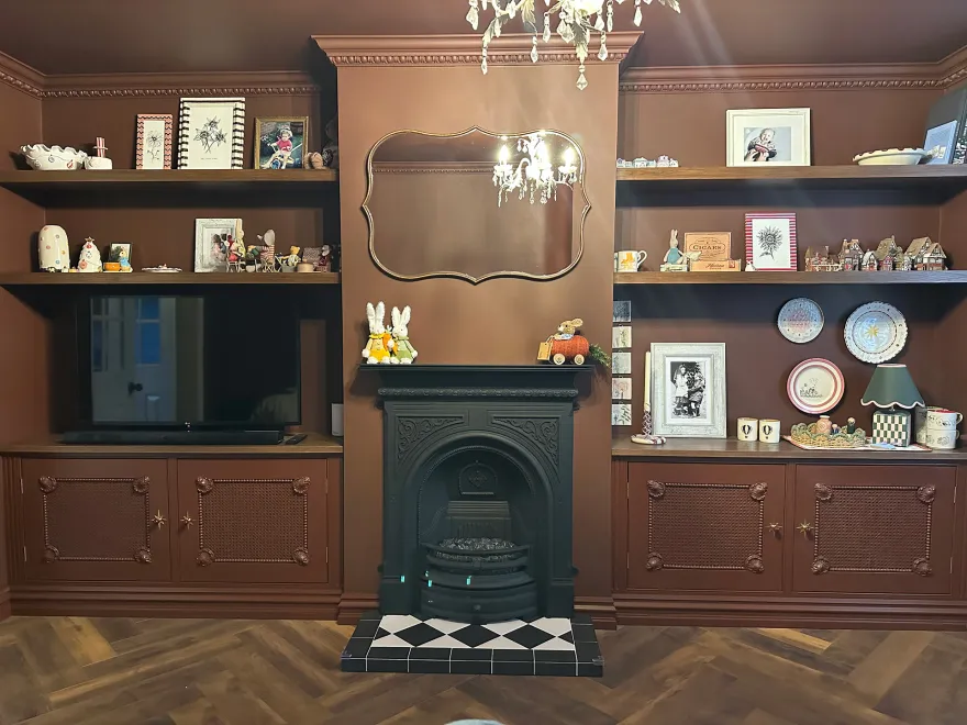 Brown painted alcove units and floating shelves around a Victorian cast iron fireplace