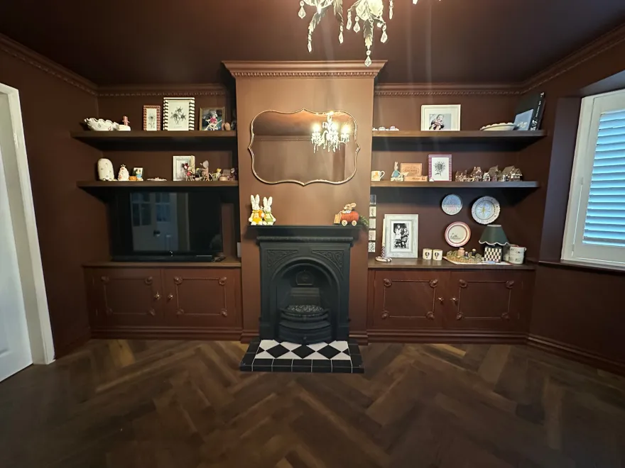 Wide view of a brown living room with fitted alcove units either side of the fireplace