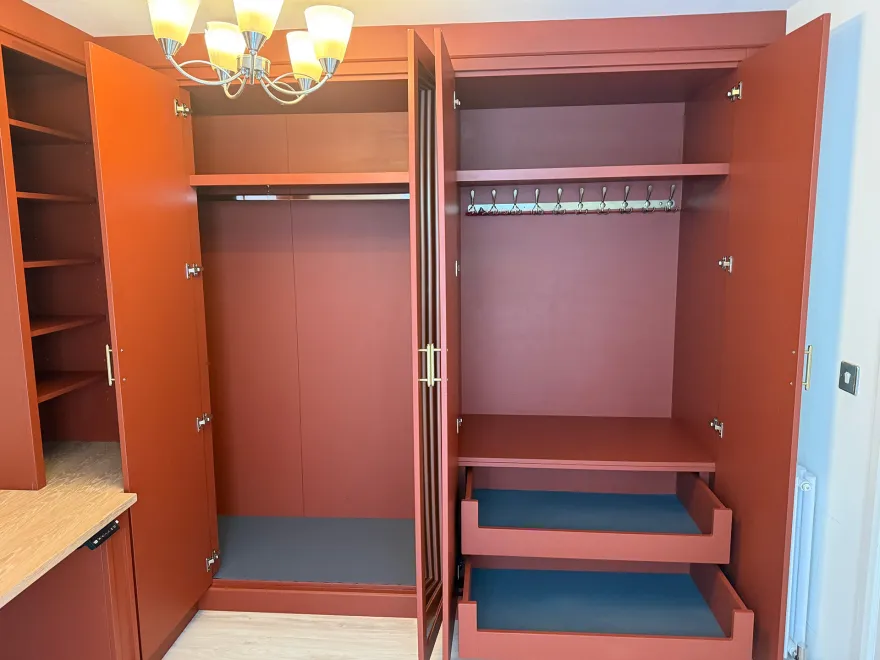 Terracotta wardrobe open to show hanging space, coat hooks and pull-out drawers