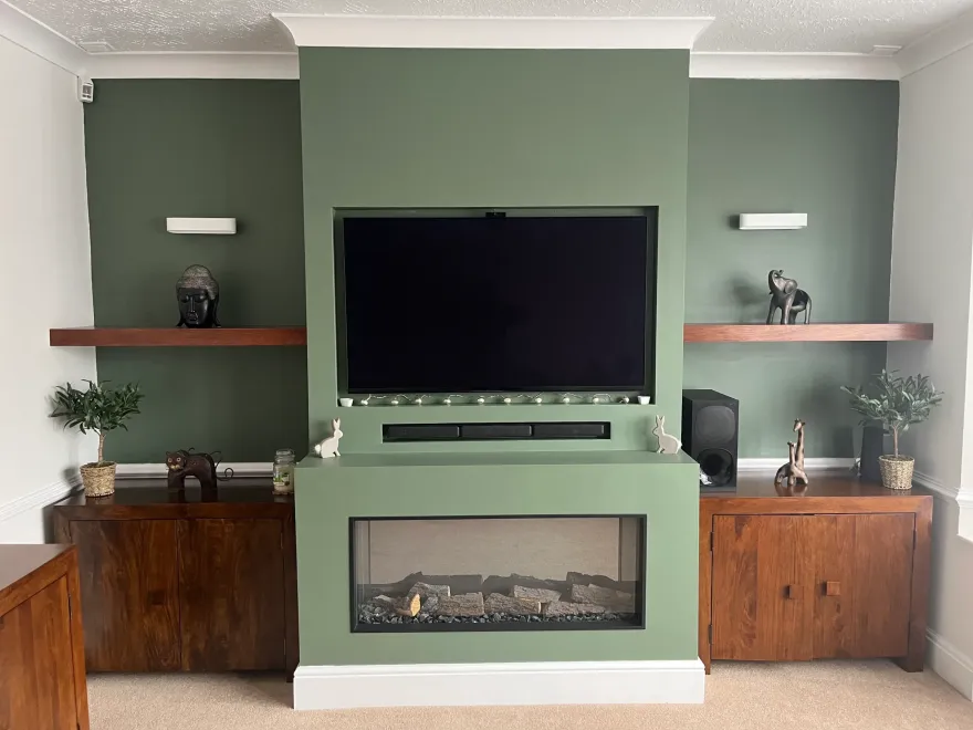 Green chimney breast media wall with an inset fire, TV and floating shelves