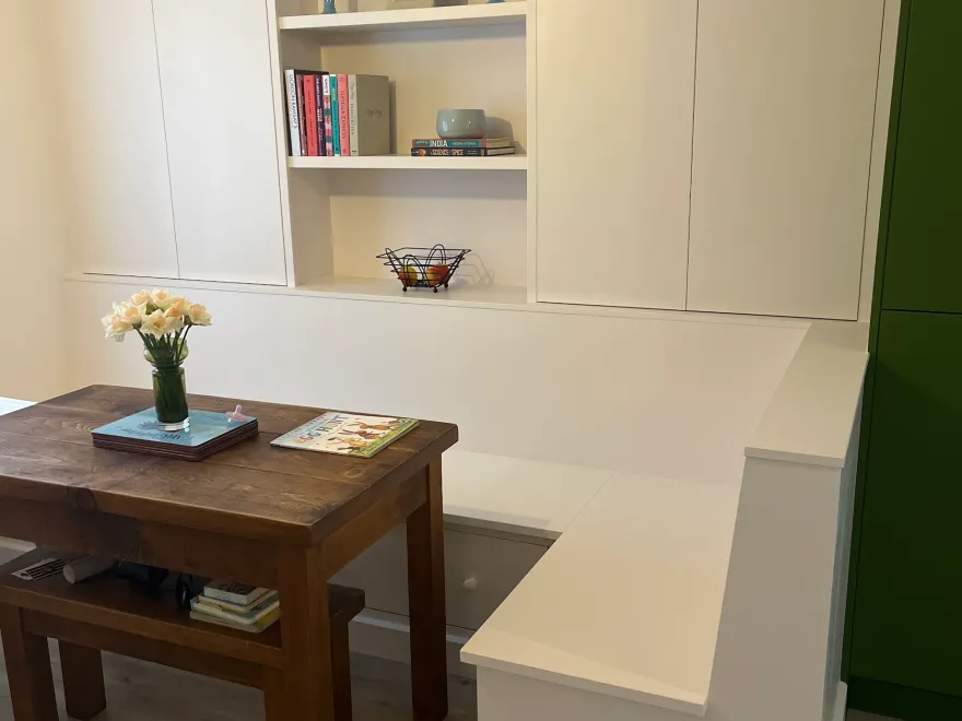 White fitted banquette seating with tall cupboards and open display shelves