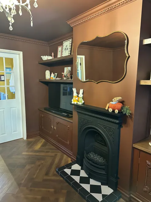 Angled view of alcove shelving, a TV cupboard and the cast iron fireplace