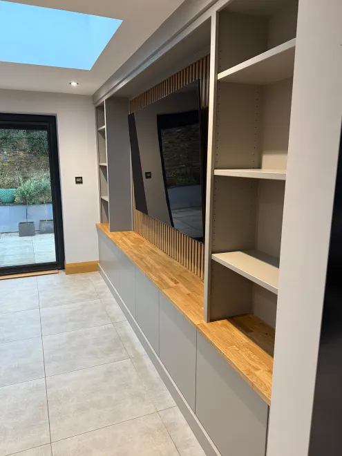 Side view of the media wall showing its oak worktop, shelving and slatted backing