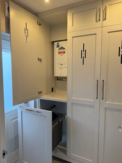 Boot room cupboards open to show a hidden boiler and a pull-out bin