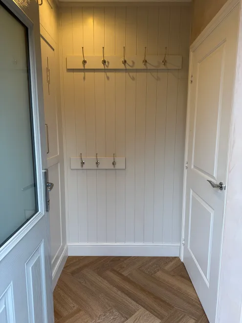 Tongue-and-groove panelled boot room nook with rows of coat hooks