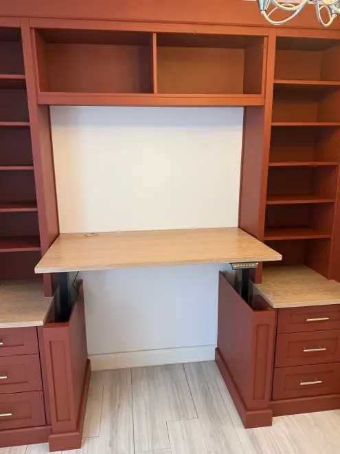 Height-adjustable oak desk raised between terracotta shelving and drawer units