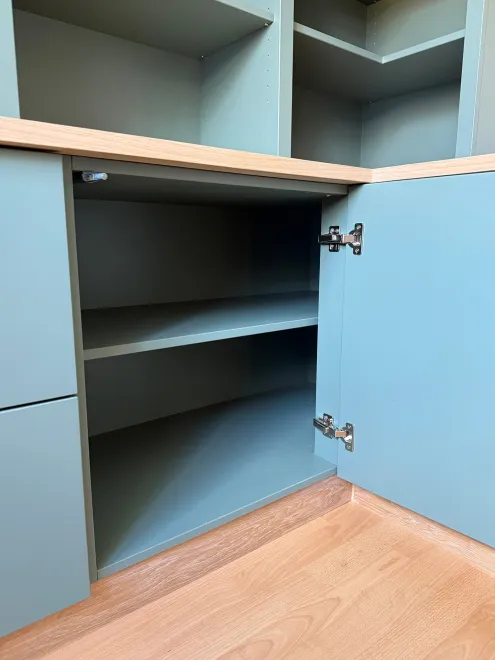 Green corner cupboard open to show shelves beneath the desk