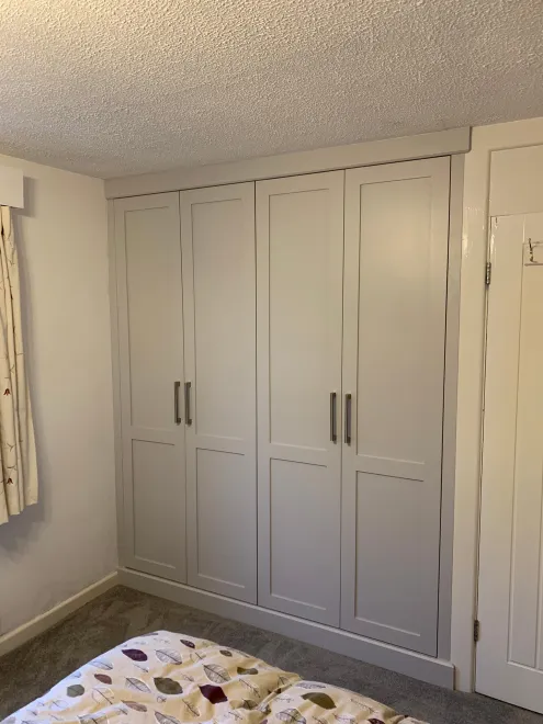 Four-door painted shaker fitted wardrobe with bar handles in a bedroom