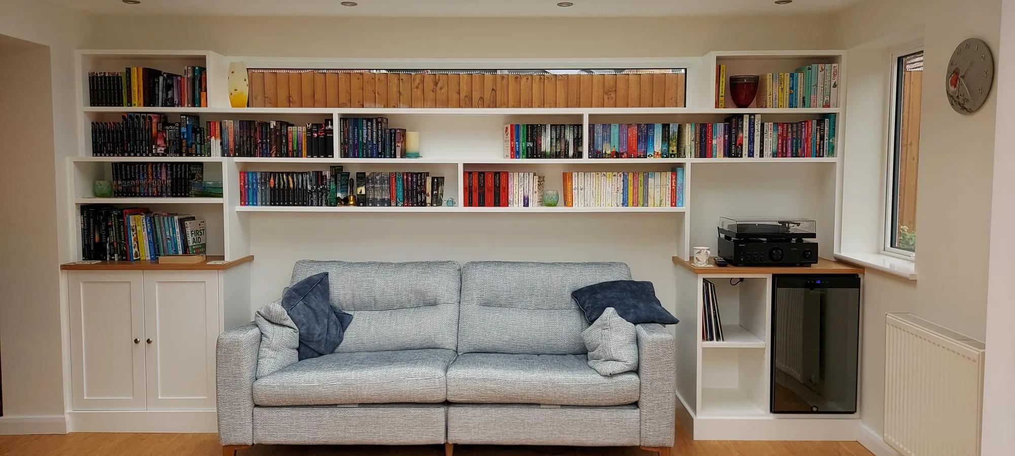 White built-in bookshelves and cupboards framing a sofa in a living room