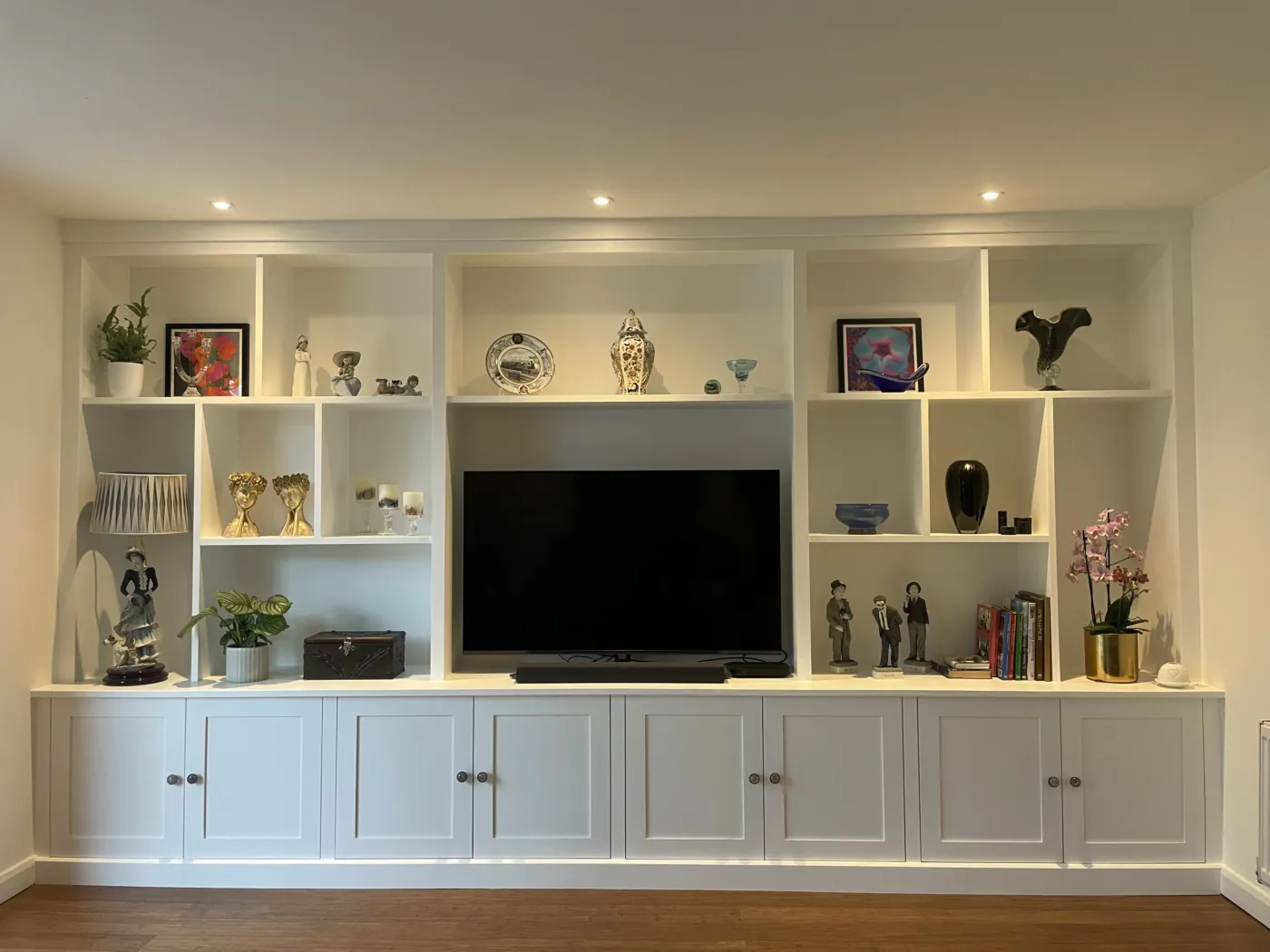 White media wall with shaker cupboards, display shelves and a TV recess