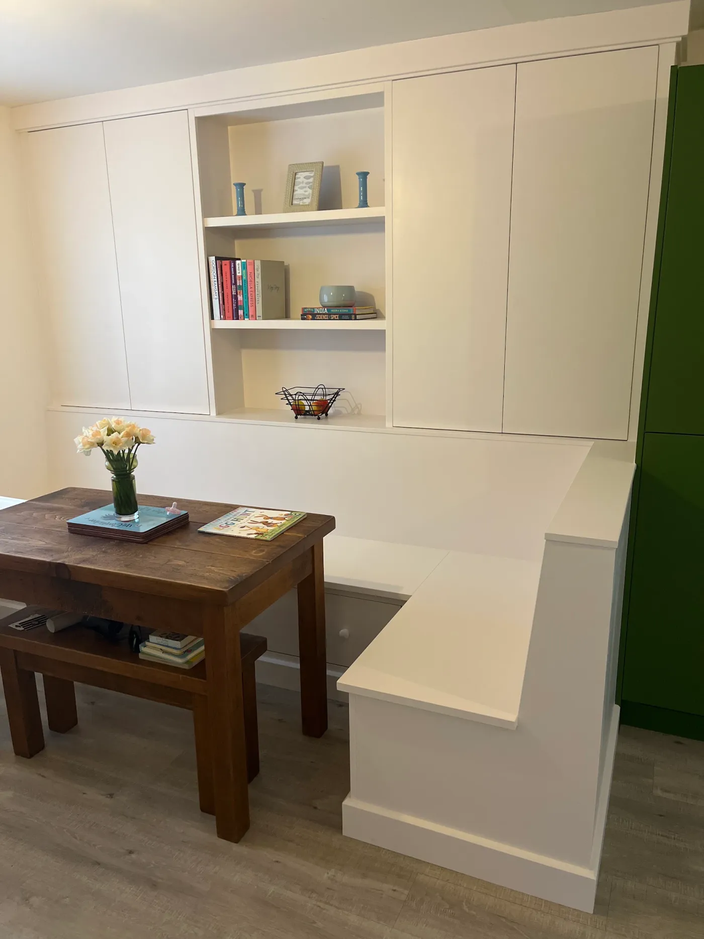 White fitted banquette seating with tall cupboards and open display shelves