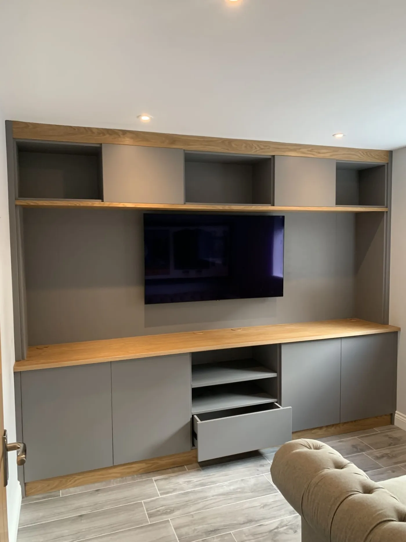 A grey media wall with an oak worktop and an open sliding drawer